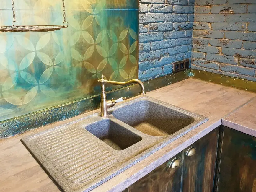 Cozy kitchen interior featuring a rustic double sink, decorative brick wall, and vibrant backsplash.