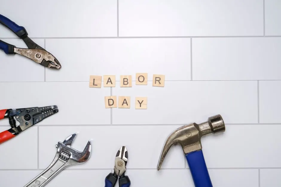 Flat lay of various tools and 'Labor Day' letters on white tiles. Perfect for Labor Day themes.